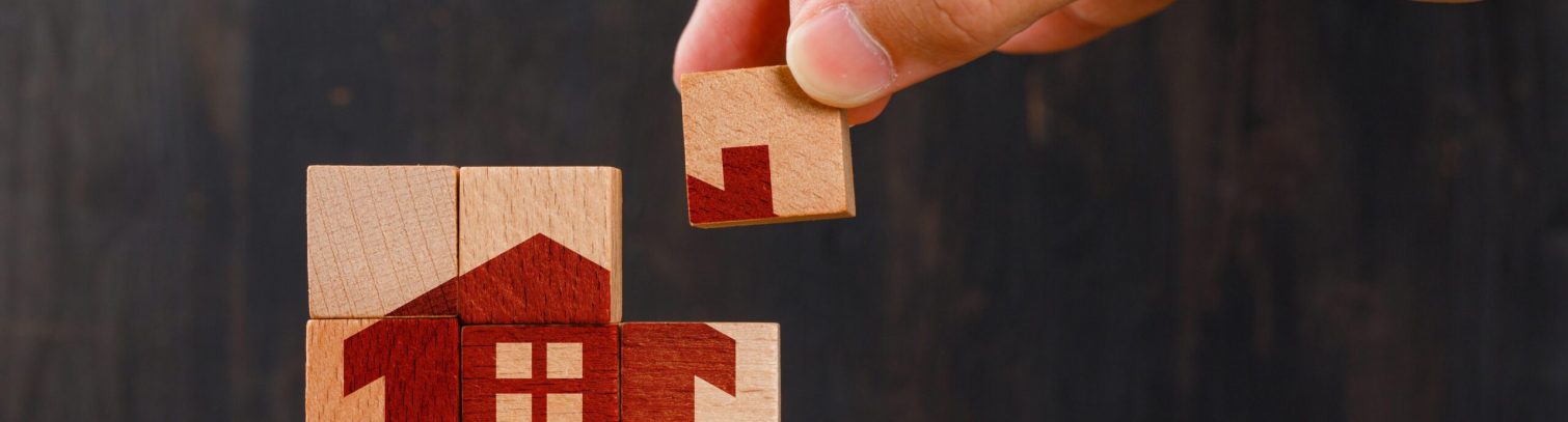 Stay at home concept on wooden background side view. hand holding wooden cube.